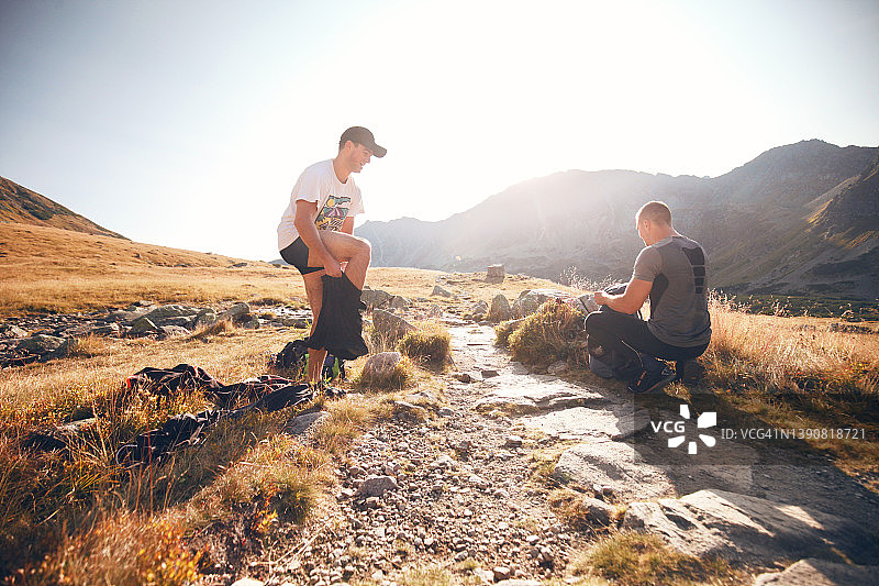 日出时分，两名男子在山中徒步旅行时更换衣服图片素材