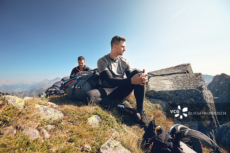 两个男人在晴朗的日子里坐在山顶上图片素材