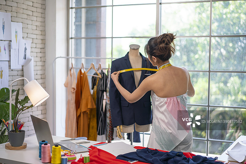 女性在男士人体模型上测量夹克尺寸图片素材