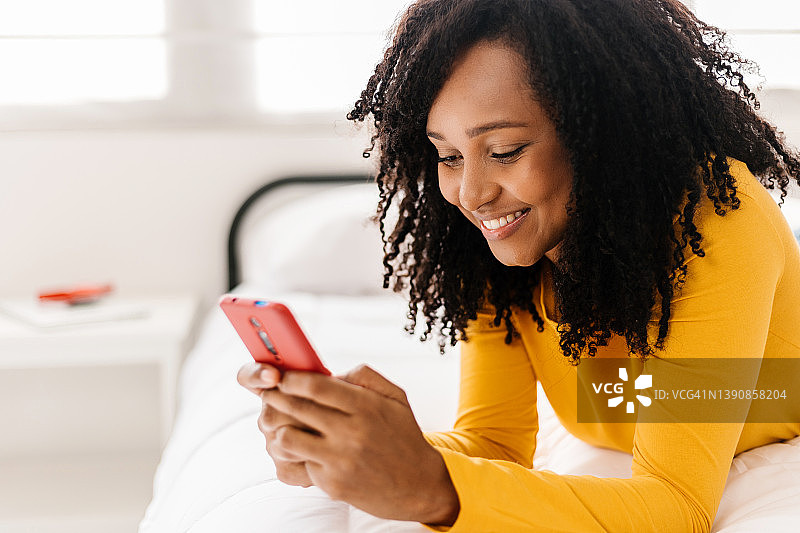 快乐的女人在床上用智能手机图片素材
