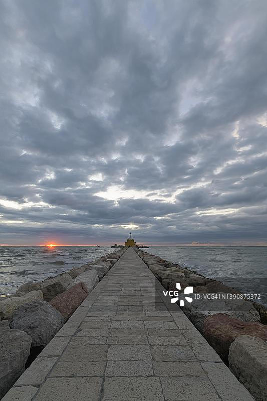 日出时威尼斯蓬塔萨比奥尼的堤坝和灯塔图片素材