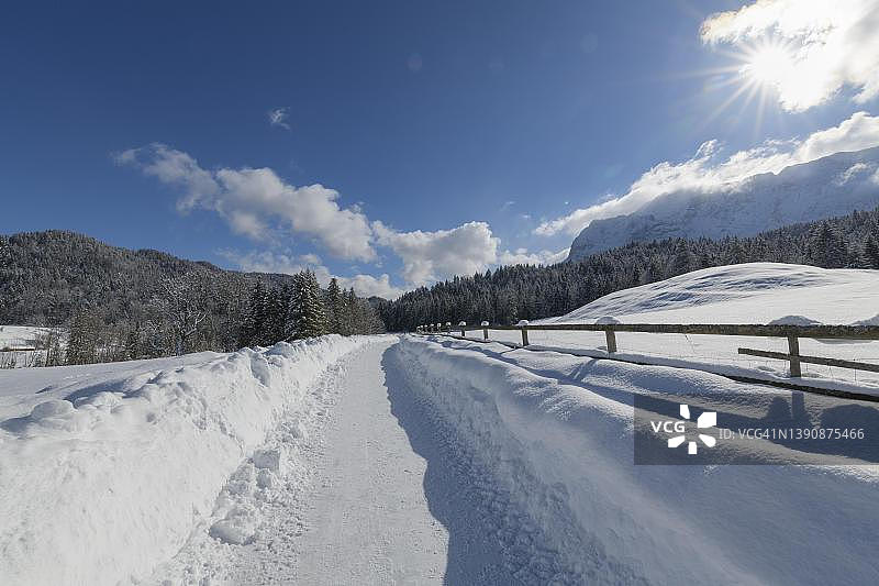 冬季阳光下的道路，位于德国巴伐利亚阿尔卑斯山图片素材