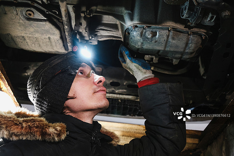 汽车修理工在车库修理汽车，更换机油图片素材