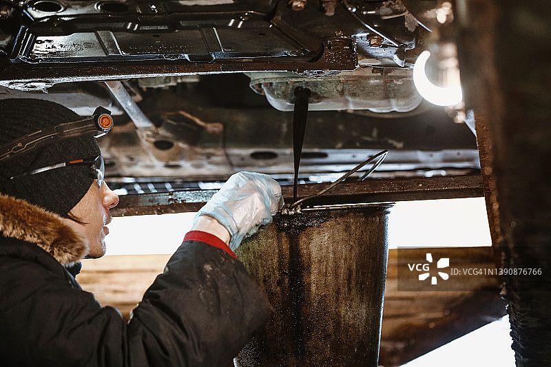 汽车修理工在车库修理汽车，更换机油图片素材
