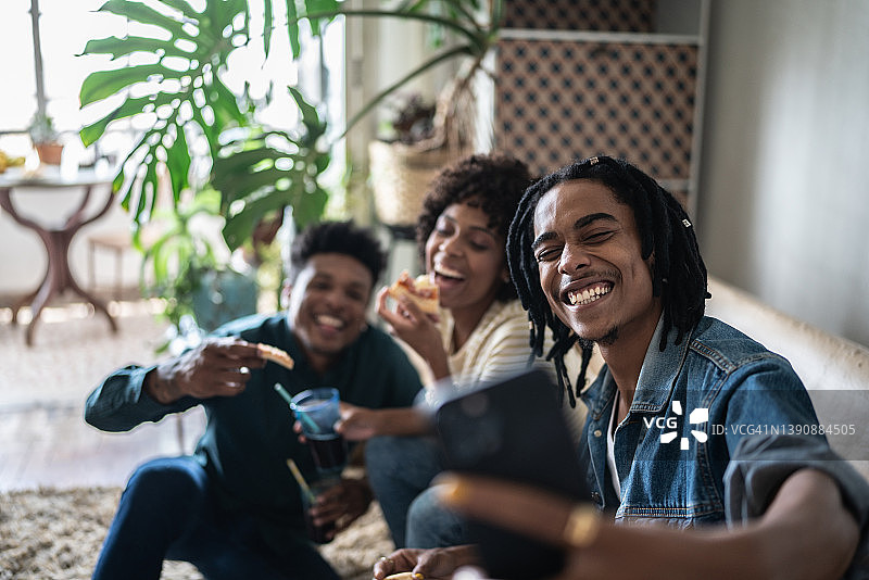 朋友们在家吃披萨时自拍或拍摄图片素材