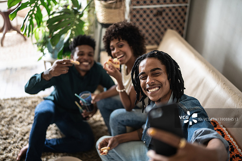 朋友们在家吃披萨时自拍或拍摄图片素材