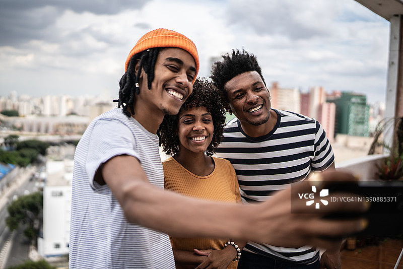 朋友们在公寓阳台上用手机自拍图片素材