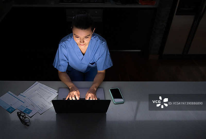 医生在家用笔记本电脑工作到深夜图片素材