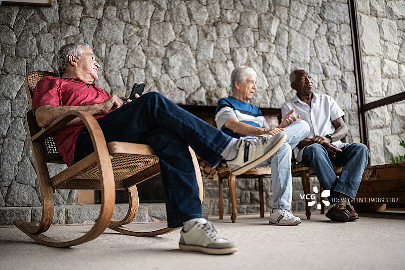 坐在摇椅上使用智能手机的年长男人图片素材