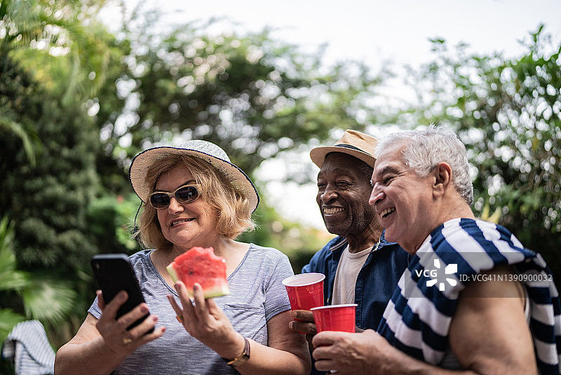 老年朋友在泳池派对上用手机自拍图片素材