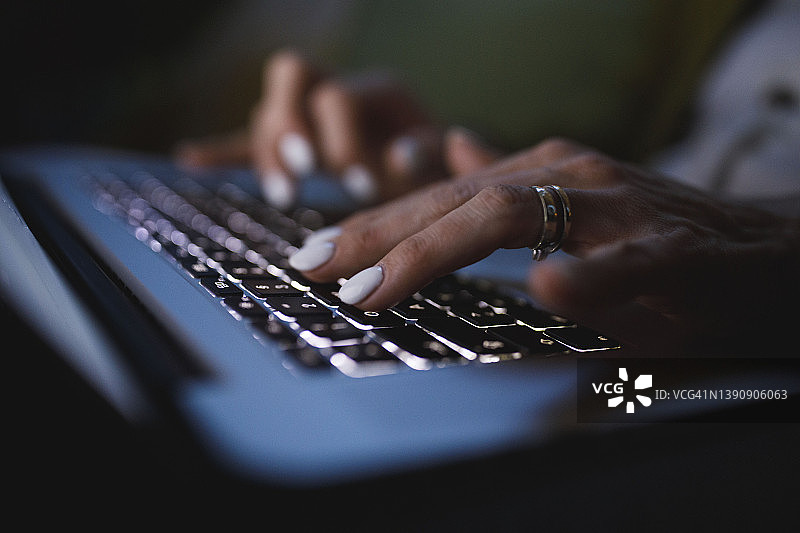 夜晚，女人在笔记本电脑键盘上输入数据图片素材