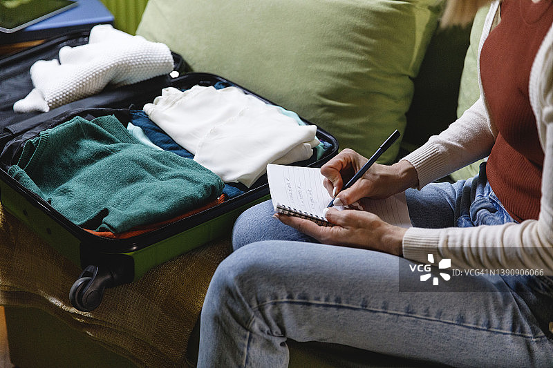 女人写一张清单，上面列着她为度假装在手提箱里的东西的剪辑照片图片素材