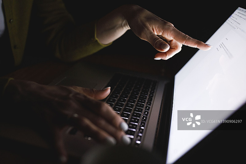 女人用手指指向笔记本电脑屏幕上的文字图片素材