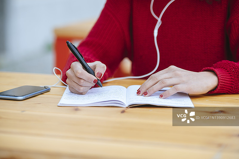 在笔记本上写字的女人特写图片素材