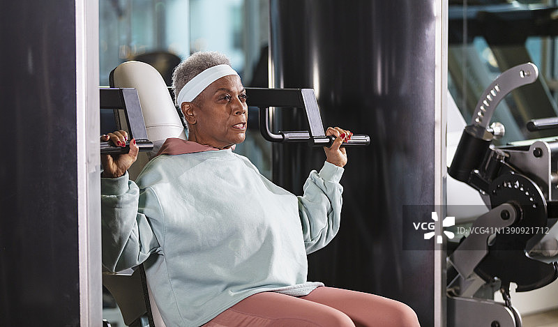 在健身房做肩上推举的年长的非裔美国女人图片素材