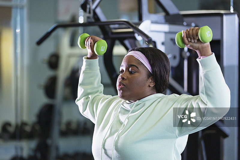 非裔美国妇女在健身房举哑铃图片素材