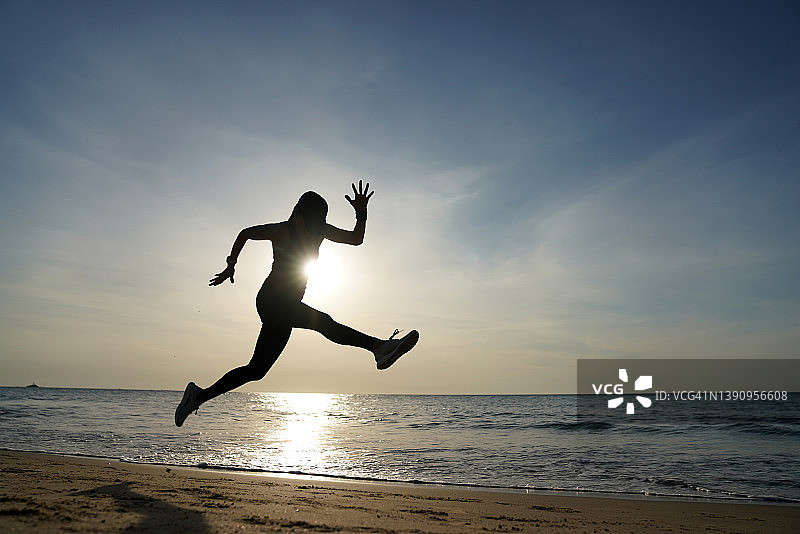 在海滩上跑步的运动女性剪影图片素材