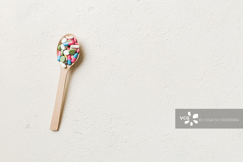彩色背景木勺中的维生素胶囊图片素材