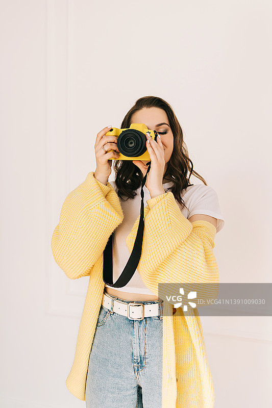 微笑的女摄影师在白色背景上手持相机图片素材