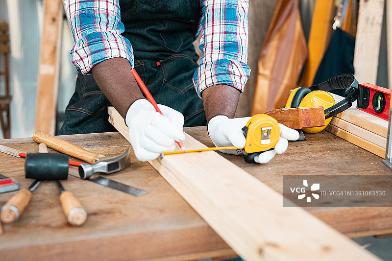 木匠在木工车间用卷尺和铅笔制作木桌图片素材
