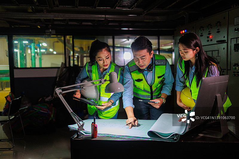 一群亚洲工程师在夜班制造车间使用电脑工作图片素材