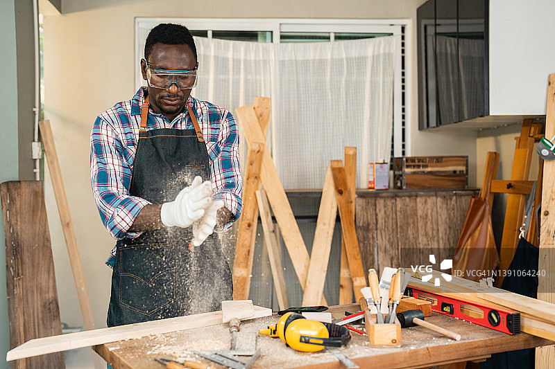 在工作坊工作的黑人手工艺人，正在清除手上的木屑图片素材