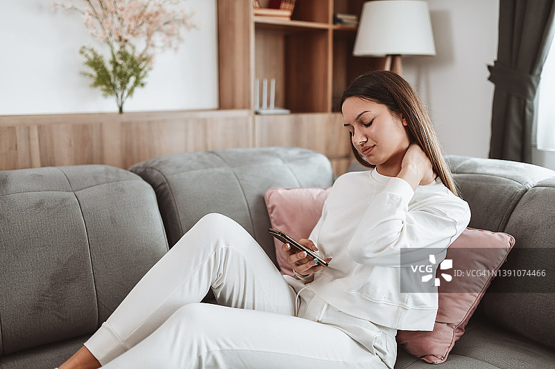 整天躺着看智能手机导致颈部疼痛的女人图片素材