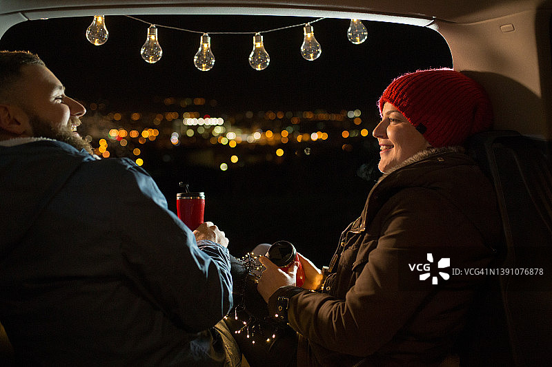 情侣坐在汽车后备箱里喝热茶图片素材