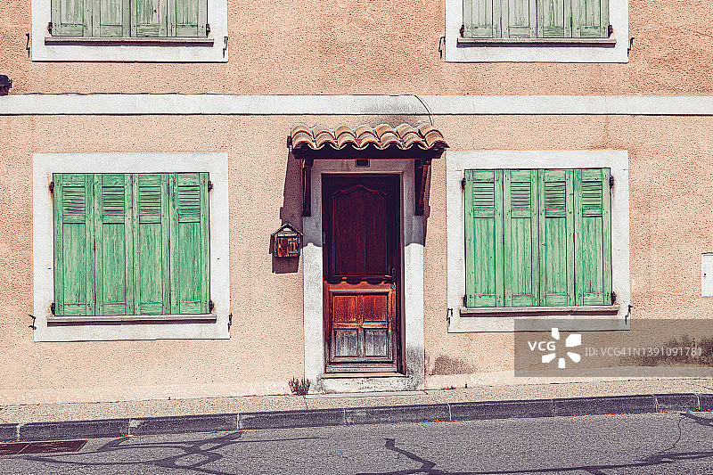 带有木制经典门、橙色墙壁和封闭式绿色百叶窗的历史建筑立面图片素材
