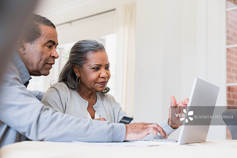 年长的男人帮助妻子进行网上购物图片素材