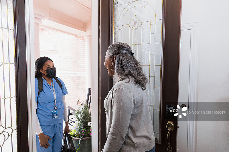 年长的女人在前门迎接家庭护理护士图片素材
