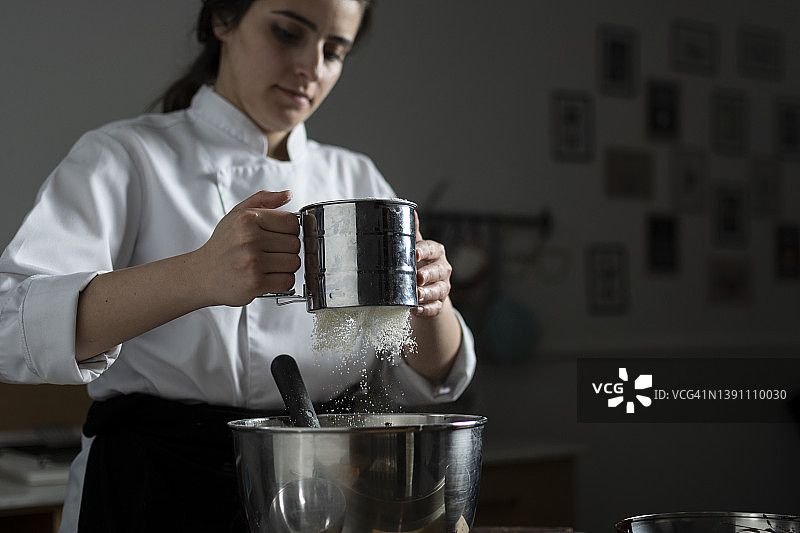 烘焙女厨师用筛子筛面粉图片素材