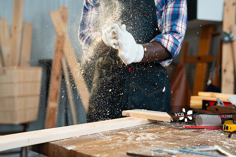 木匠在加工木材后清理工作手套上的锯末图片素材