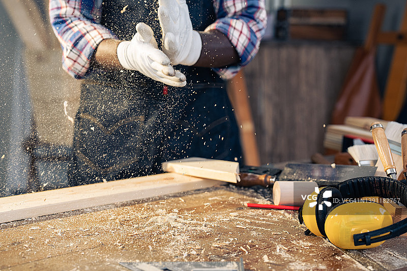 戴着工作手套的木匠拍手去除锯末图片素材