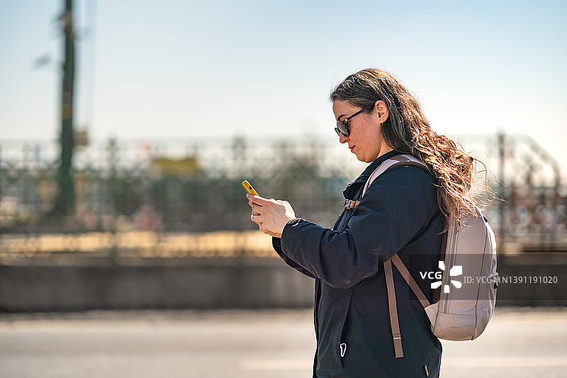 在城市街道上使用手机的女游客图片素材