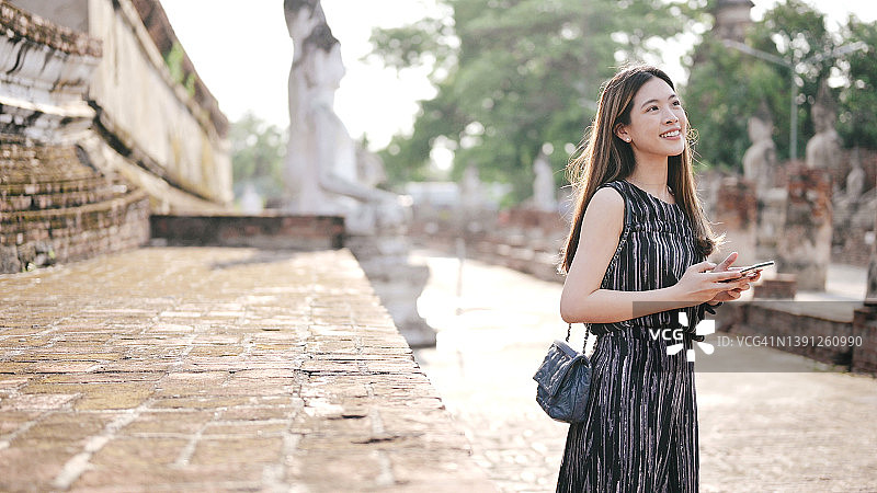 使用5G互联网的女子在泰国阿瑜陀耶府柴蒙坤寺顶部享受视频社交短片日落图片素材