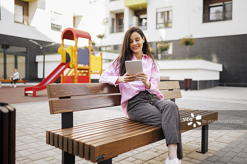 坐在公园长椅上阅读报纸和进行视频通话的漂亮女人图片素材