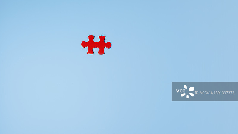 蓝色背景上的单块红色拼图图片素材