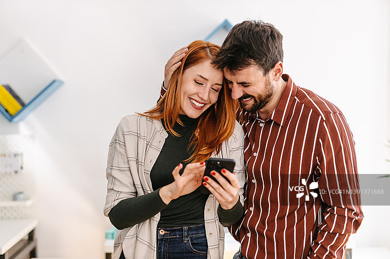 同事在联合办公空间拥抱并看手机图片素材