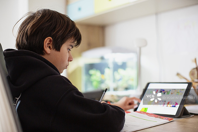 男孩在家使用平板电脑进行远程学习图片素材