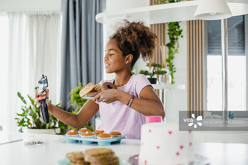 少女向她的社交媒体粉丝展示自制甜甜圈图片素材