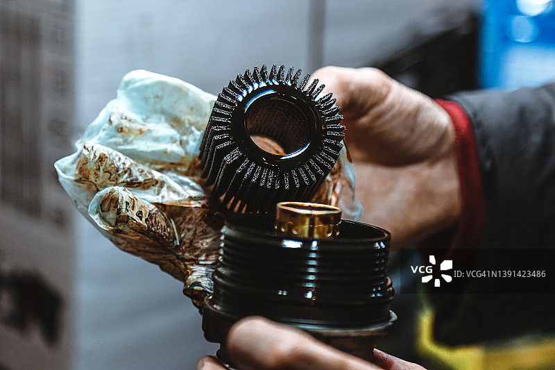 汽车修理工在车库汽车维修过程中手持脏的机油滤清器图片素材