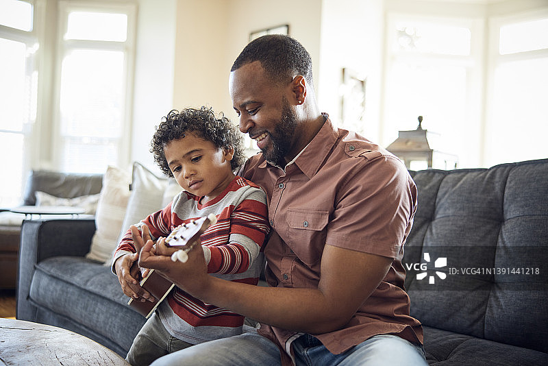父子在沙发上弹尤克里里图片素材