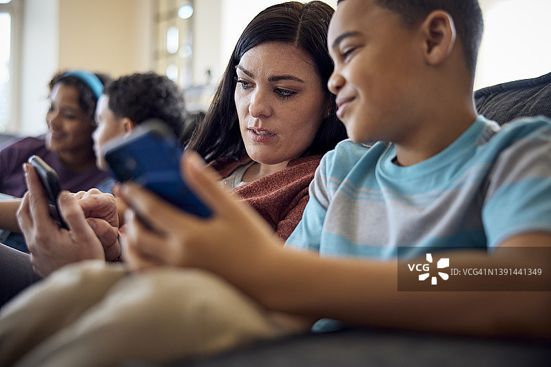 母亲和儿子一起在沙发上看手机图片素材