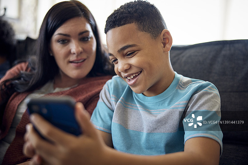 母亲和儿子一起在沙发上看手机图片素材