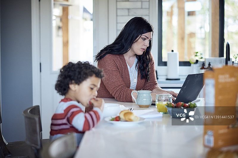 妈妈和儿子在厨房的餐桌旁一起用功学习图片素材