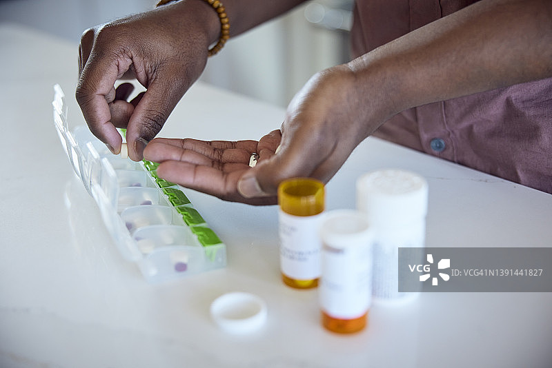 非裔美国男人将药物放入每日药盒中图片素材