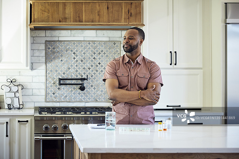 非裔美国男人将药物放入每日药盒整理器中图片素材