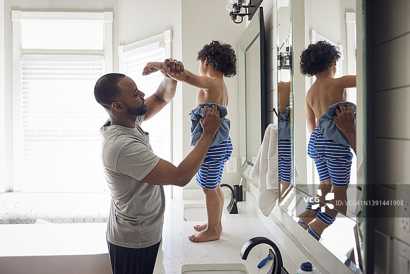 非裔美国父亲在浴室用毛巾给儿子擦干身体图片素材