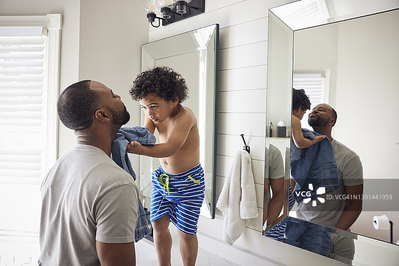 非裔美国儿子在浴室里用毛巾擦干父亲的身体图片素材